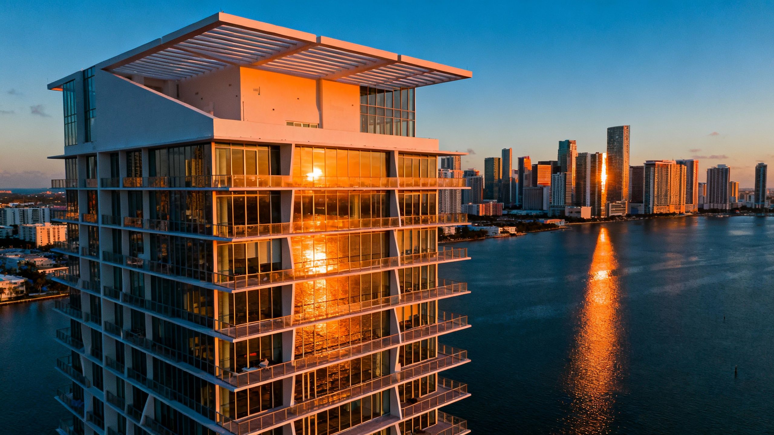 Striking modern waterfront luxury building with distinct architectural features, towering over Biscayne Bay and a vibrant Brickell skyline