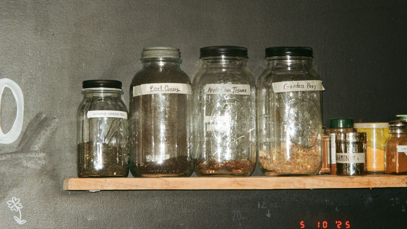 Glass jars with contents are on a shelf.