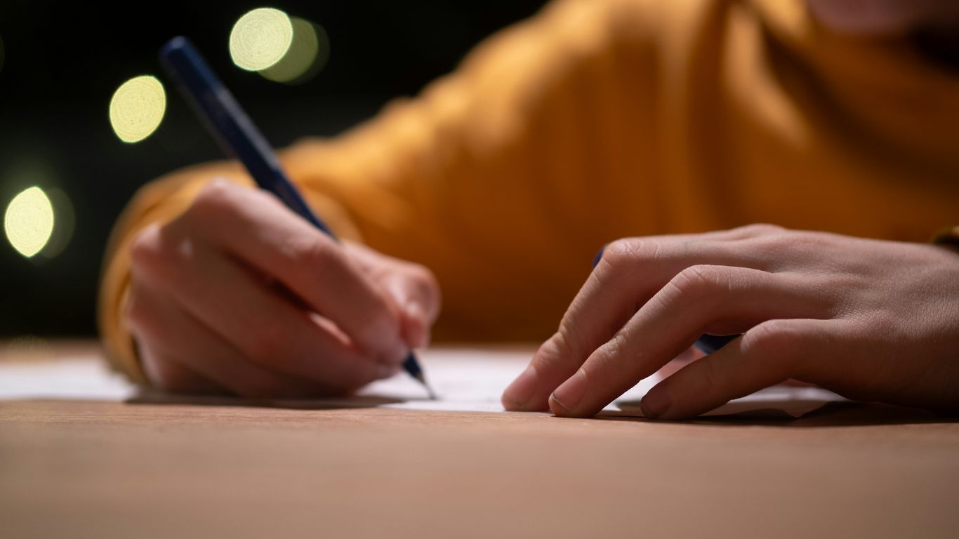 A person writing on a piece of paper with a pen