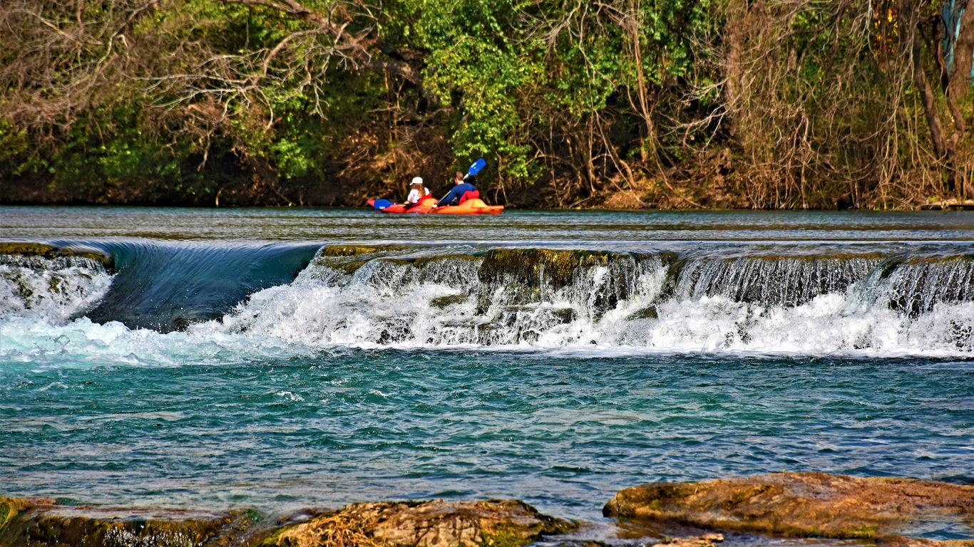 Two people kayaking down a small waterfall