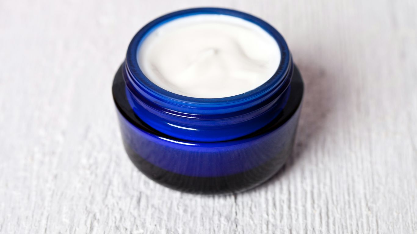 A jar of cream sitting on top of a white table