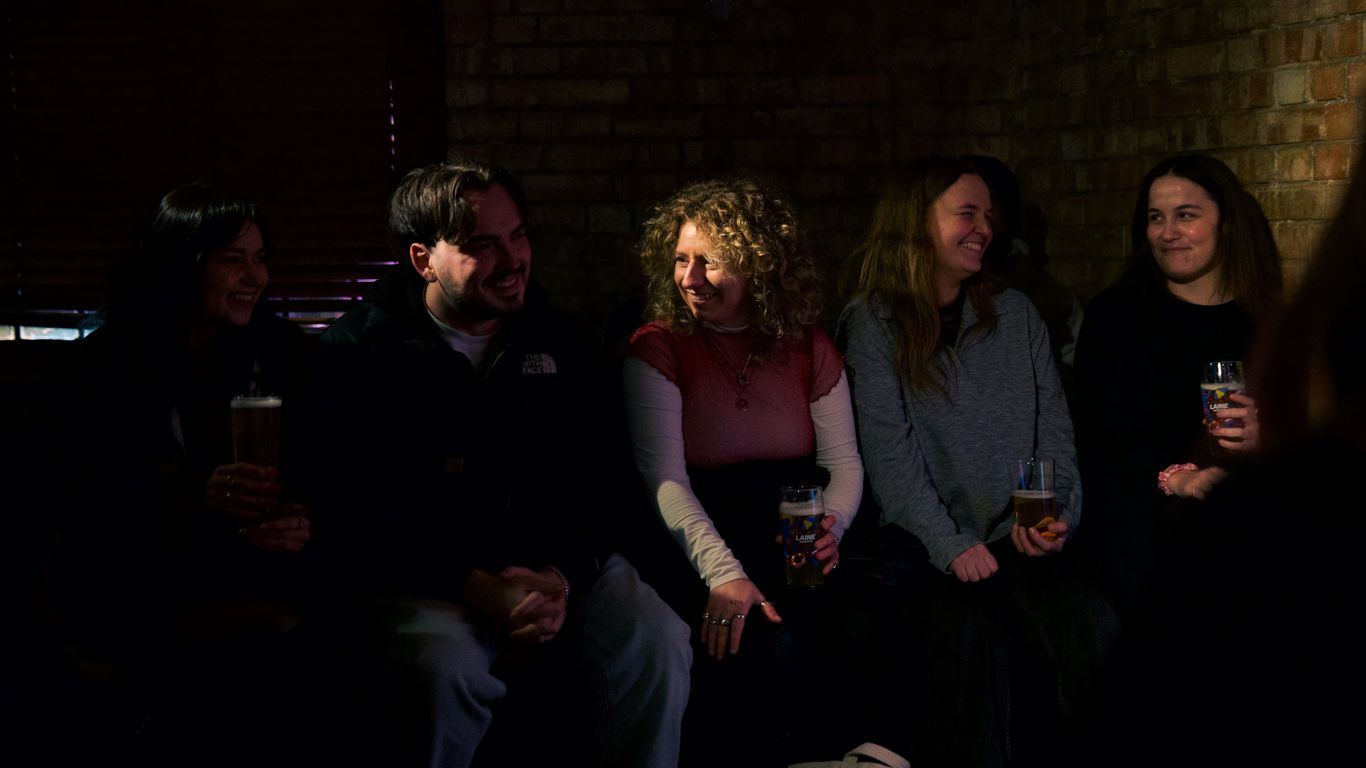 A group of people sitting and laughing in a dimly lit room.