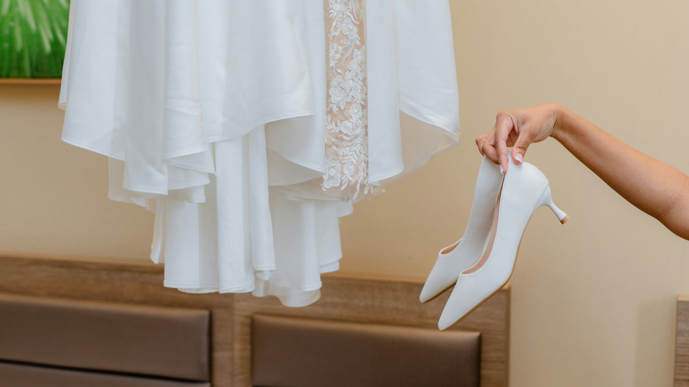 a woman holding a pair of white high heels