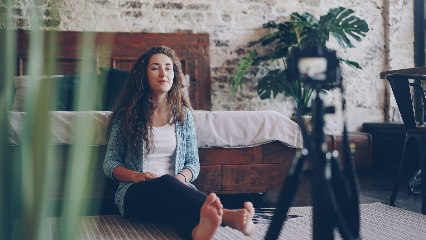Woman sitting on floor recording video with camera.