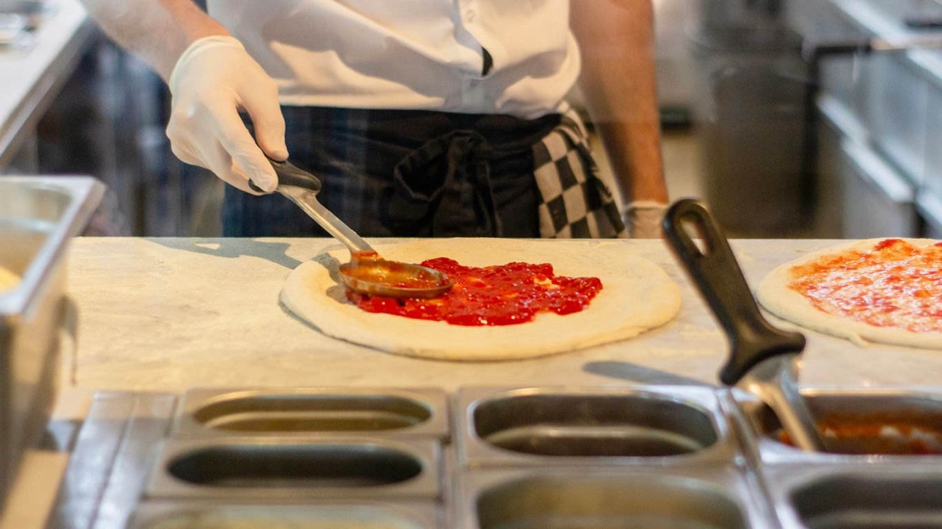 a chef is preparing pizzas in a kitchen