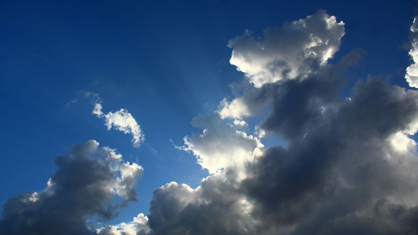 The sun is shining through the clouds in the sky