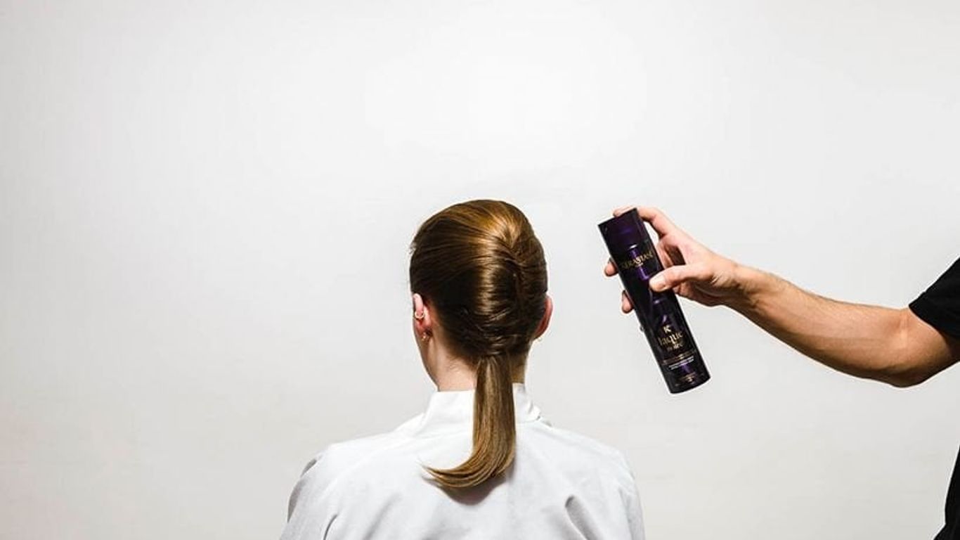 Hair styling in progress with hairspray and a neat bun.