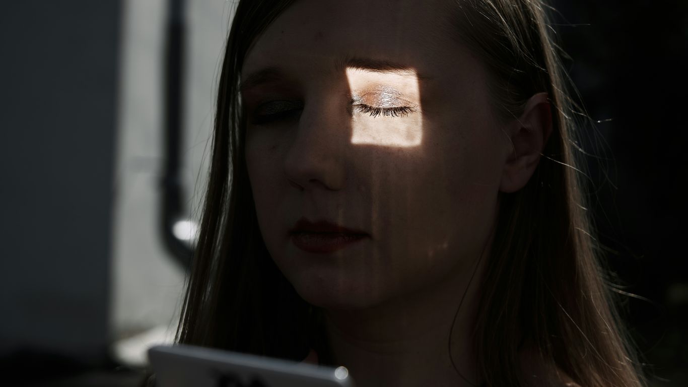 a woman with her eyes closed looking at a tablet
