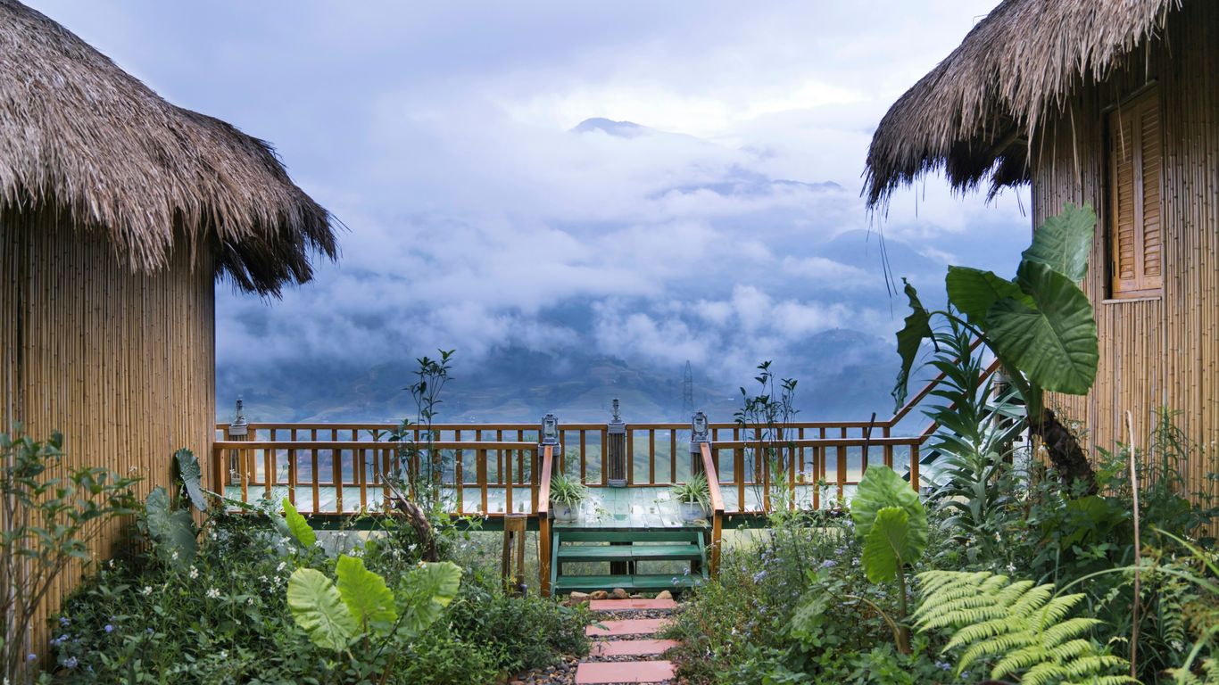 a pathway between two huts with a view of the ocean