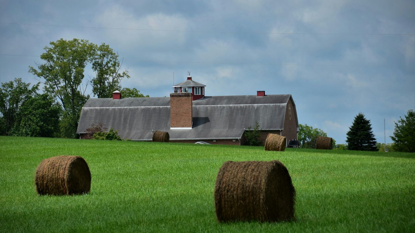 a building with bales of hay in a field