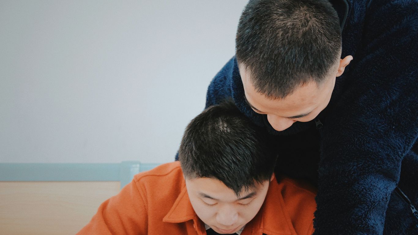 man in orange jacket beside man in blue sweater
