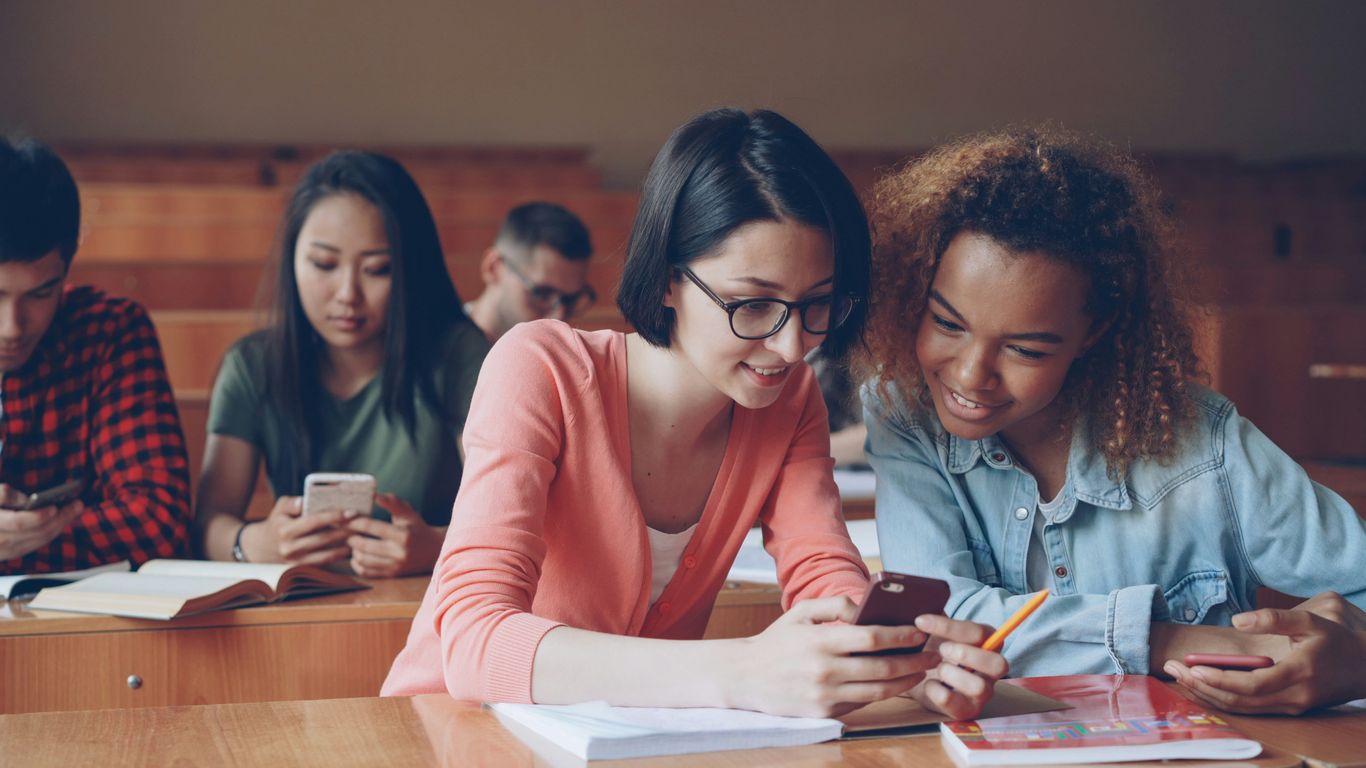Students looking at phones in a lecture hall.