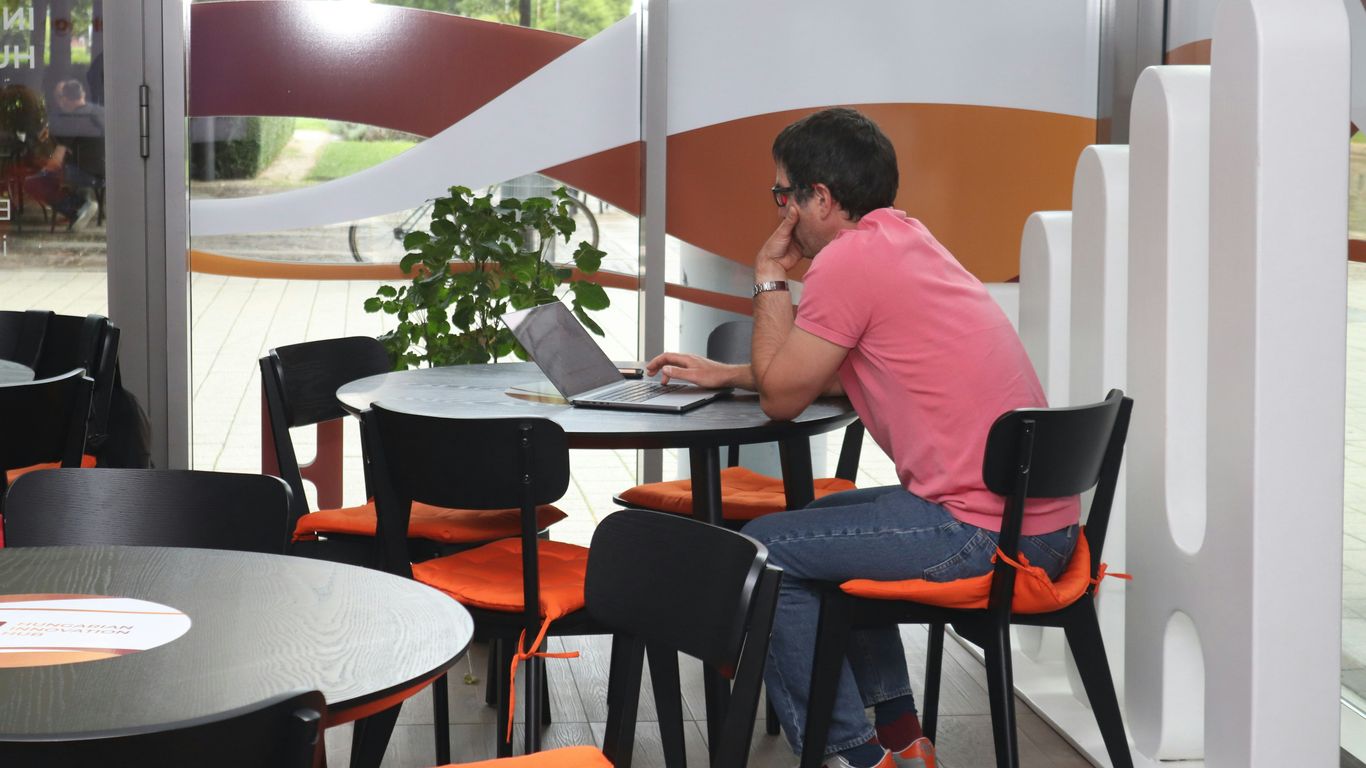 A man sitting at a table using a laptop computer