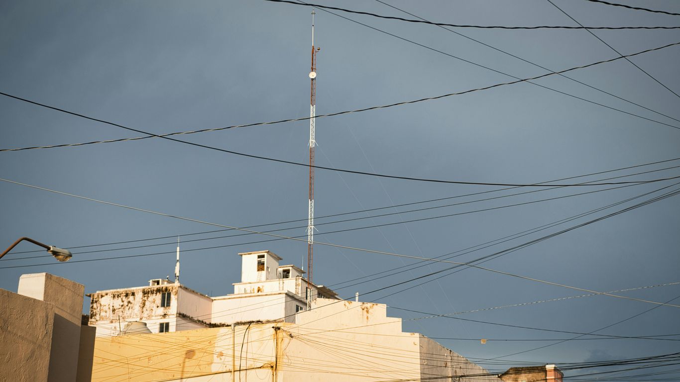 Tall antenna tower above buildings with many electrical wires
