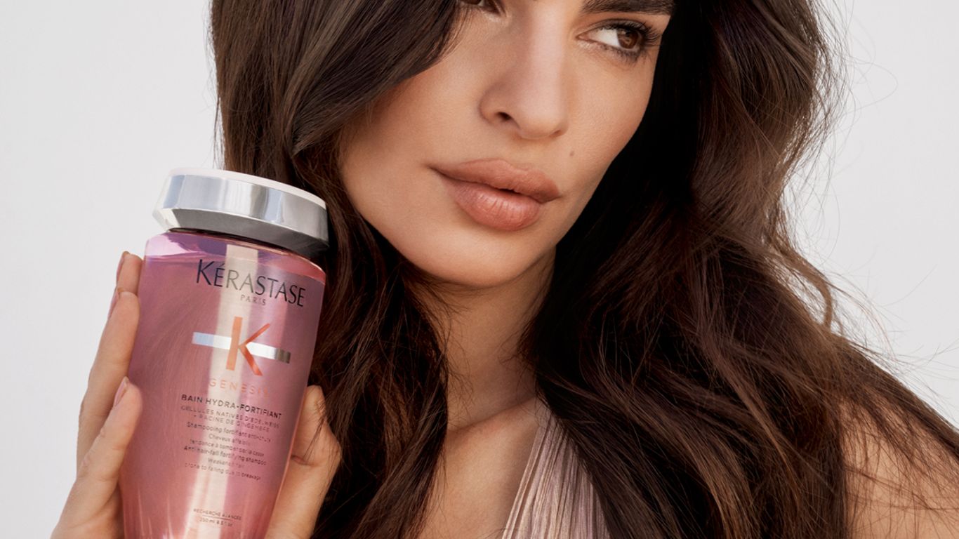 Person holding haircare product, looking calmly at the camera.