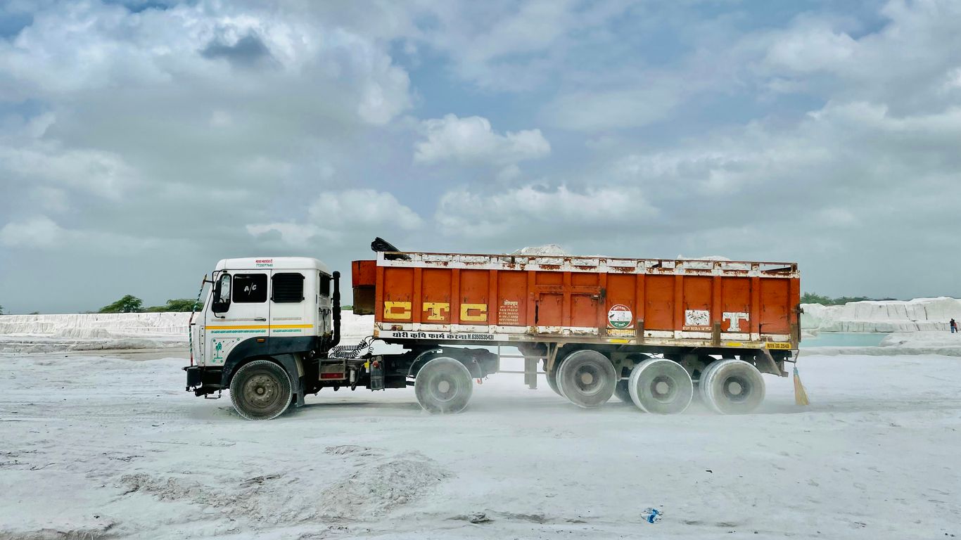 a dump truck driving on a sandy beach