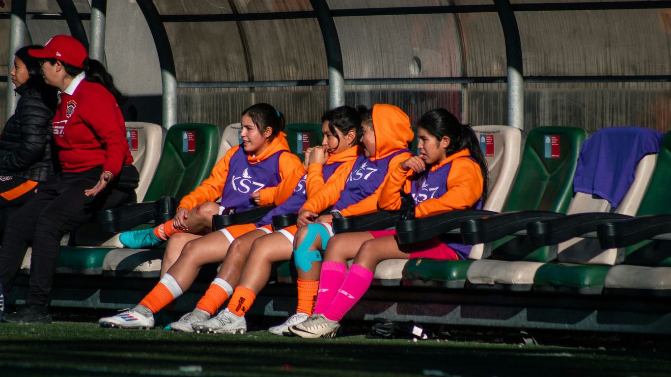 Soccer players sit on the bench during a match.