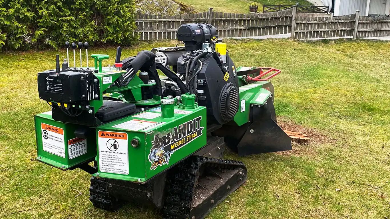 Tree stump grinder on grass, showcasing its machinery and controls.