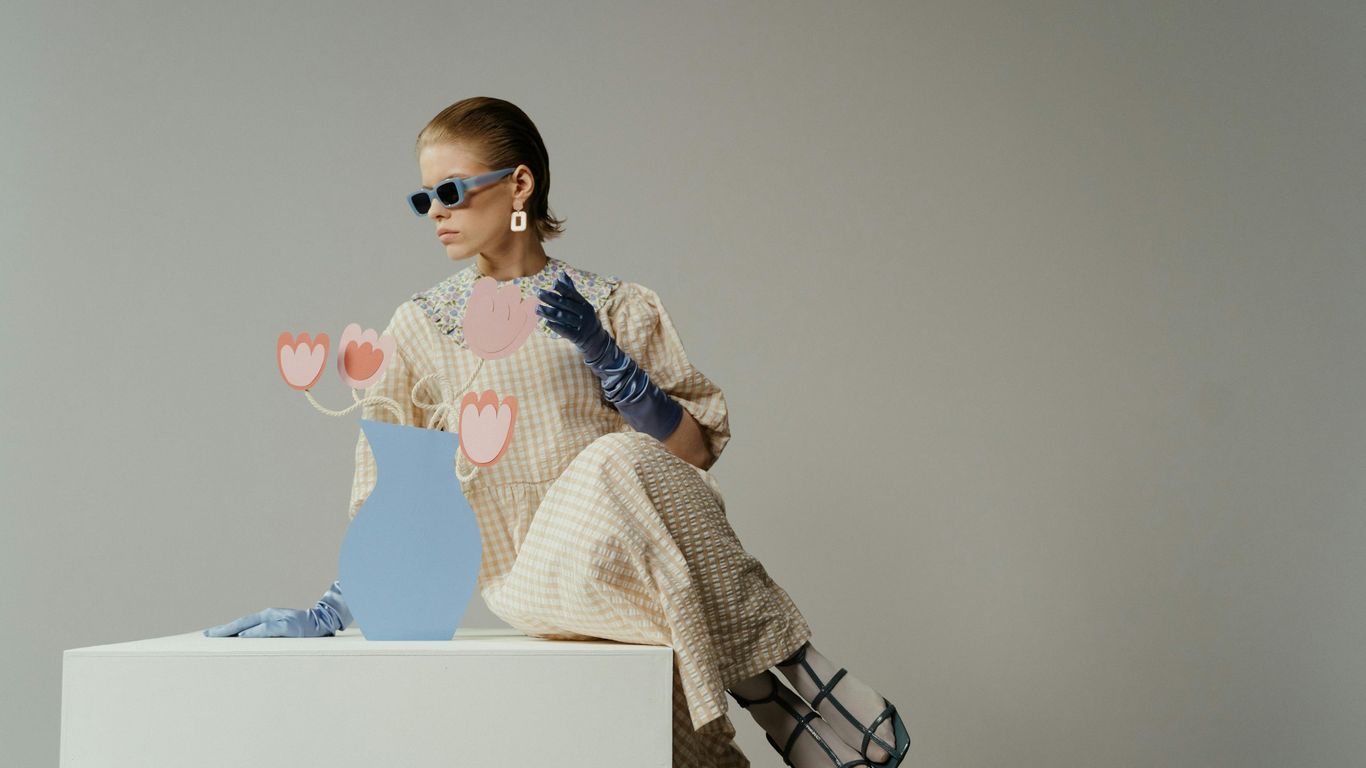 Person in a checkered dress with blue gloves and sunglasses.