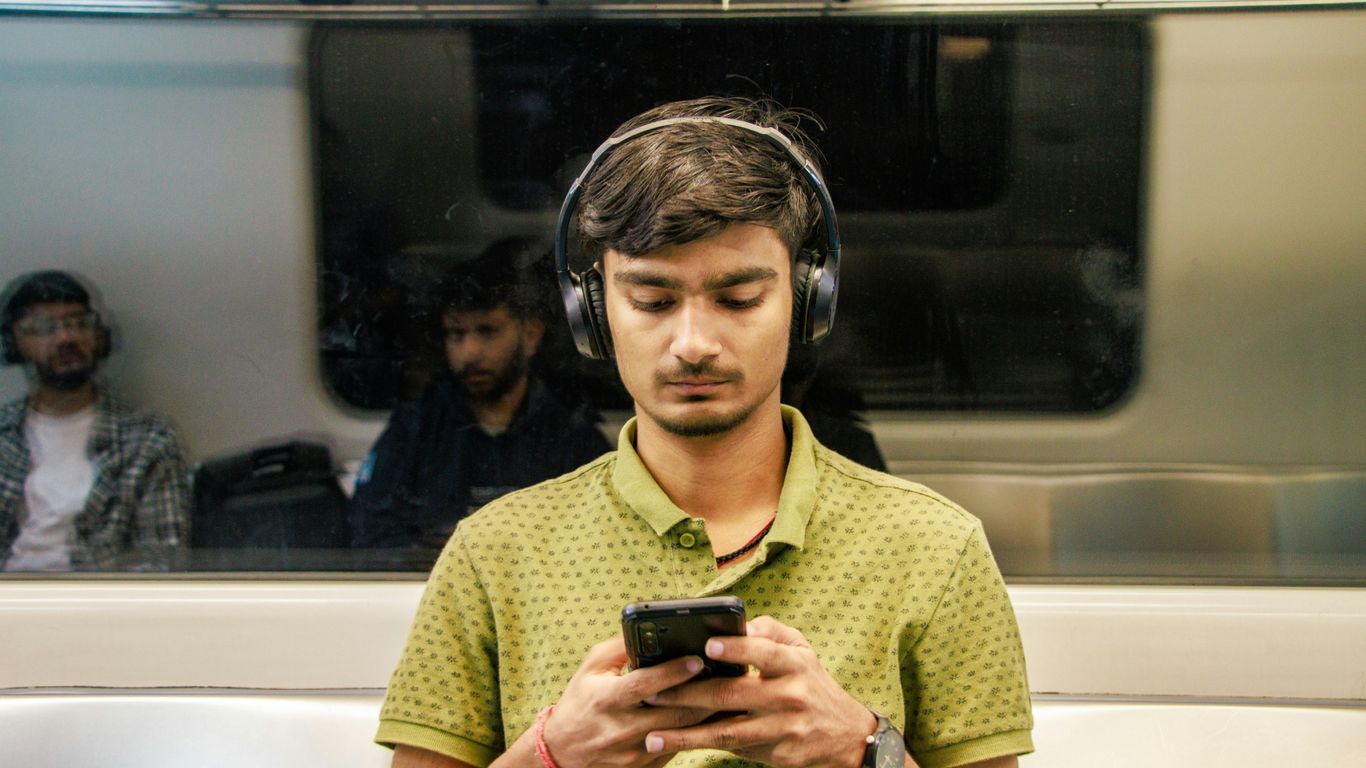 a man wearing headphones is looking at his cell phone