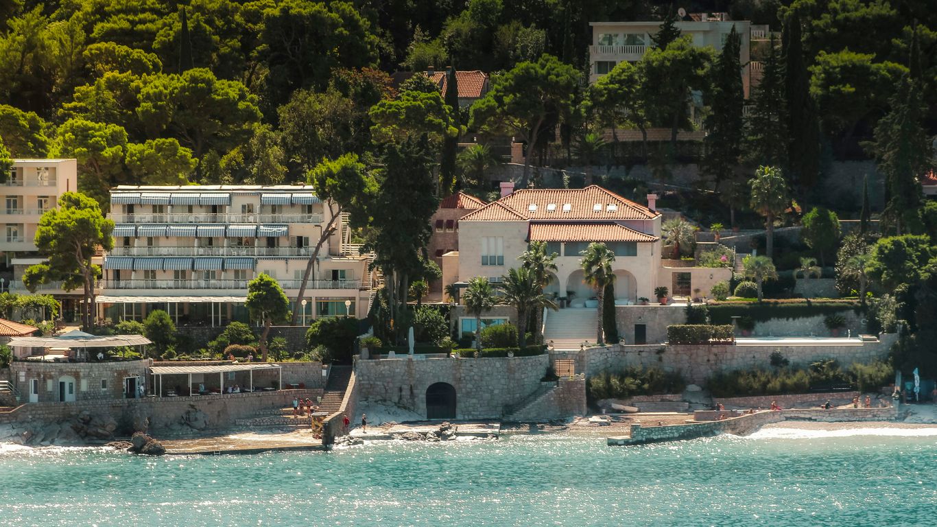 Coastal buildings nestled among lush green trees by the sea
