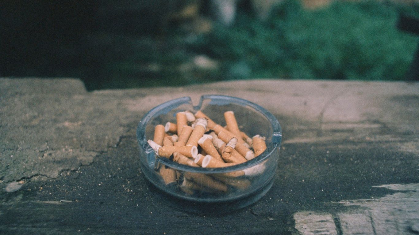 a glass bowl filled with cigarettes sitting on top of a wooden table