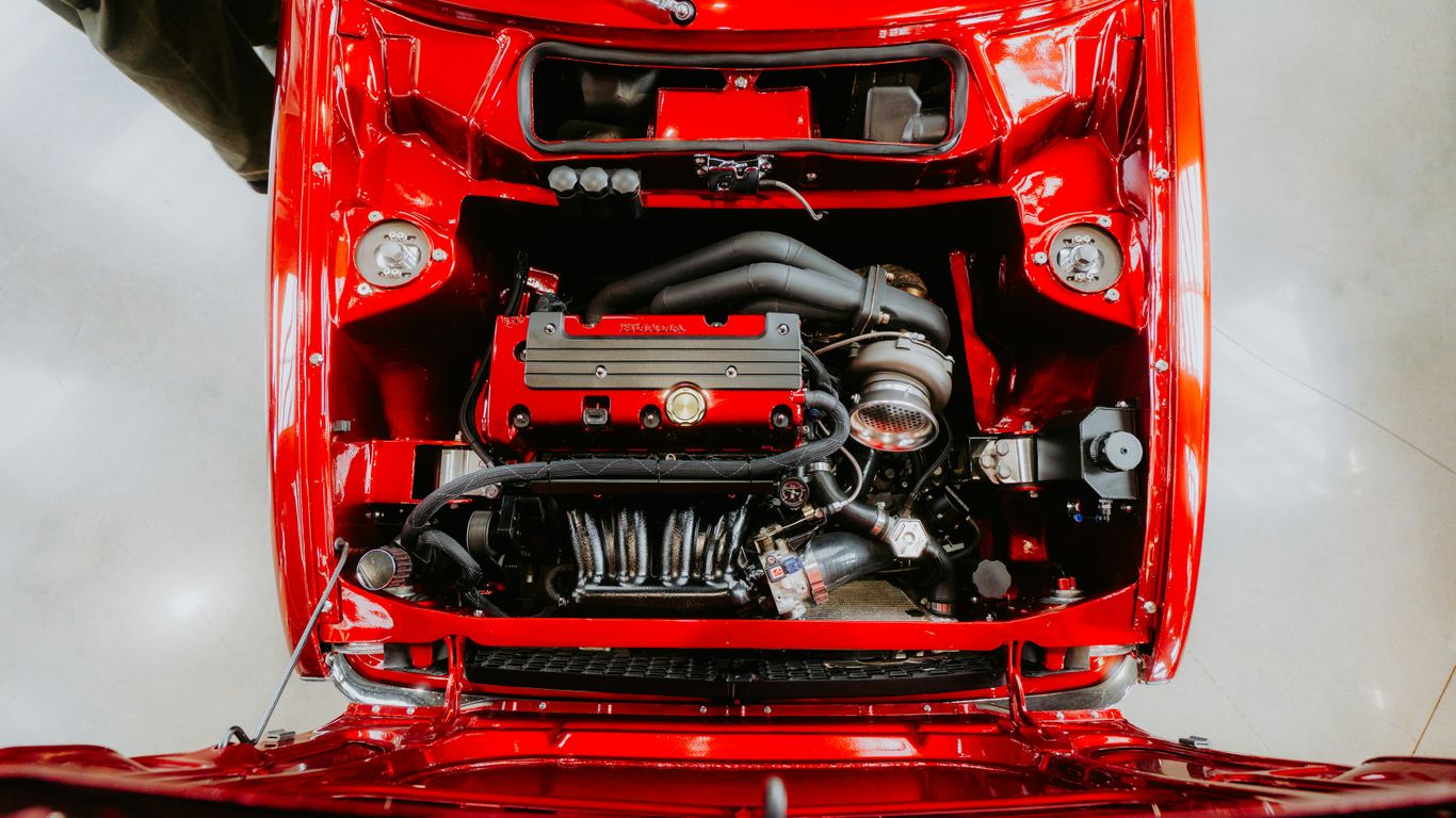 A shiny, red car engine is displayed open.