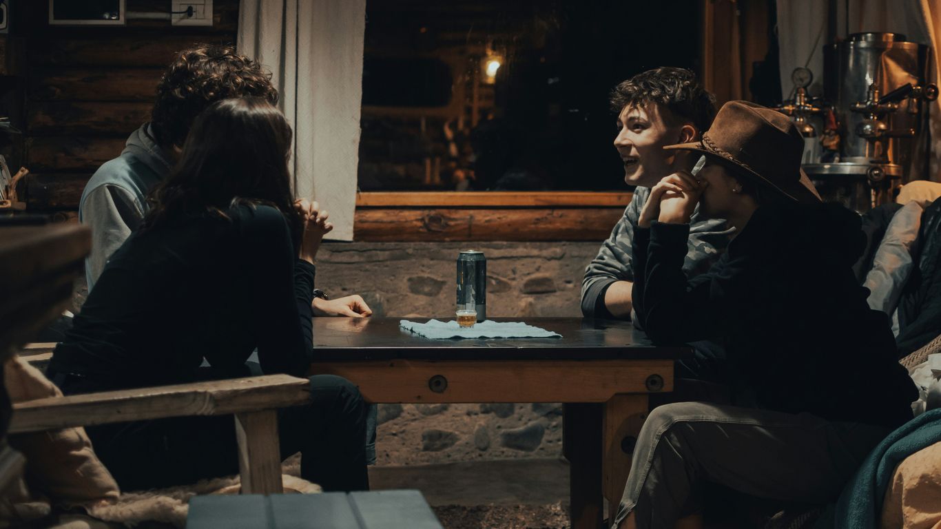 man in black jacket sitting on brown wooden chair