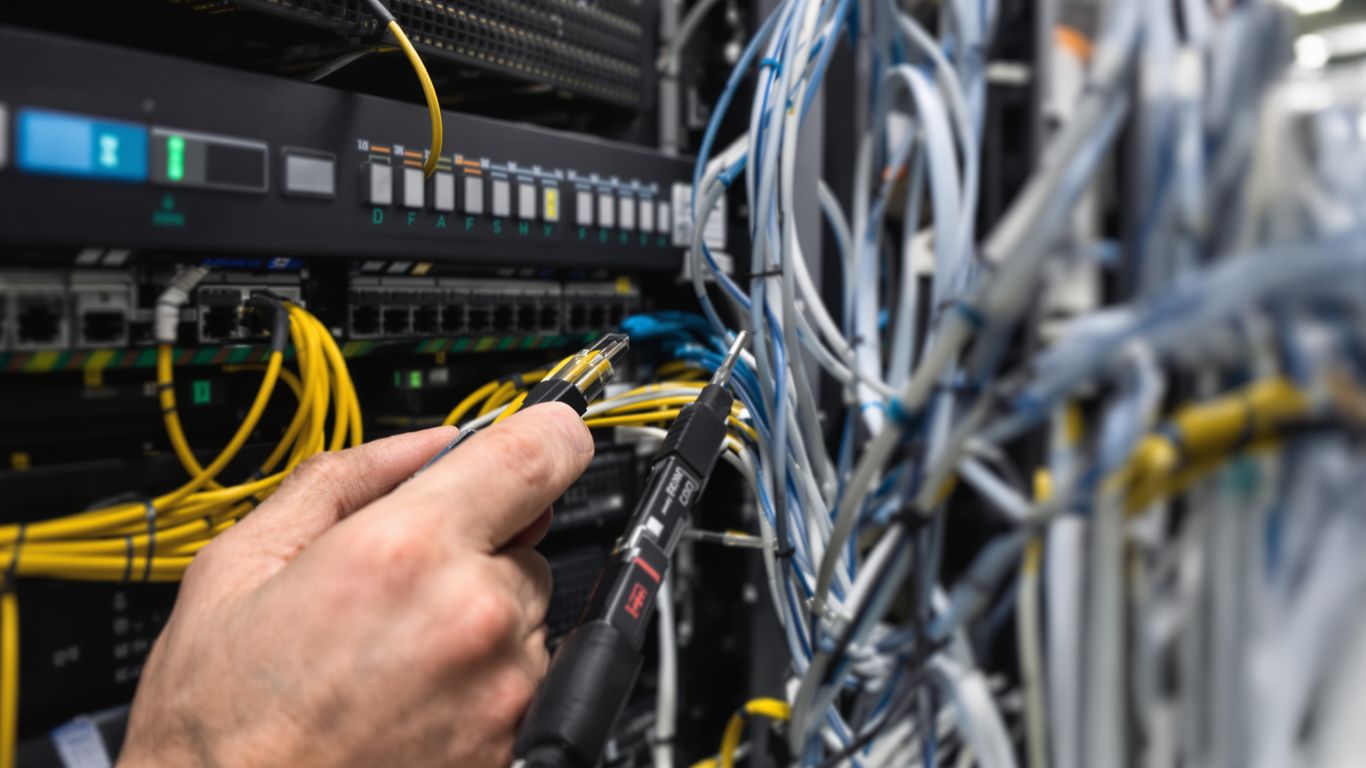 Technician connecting network cables in a server room.