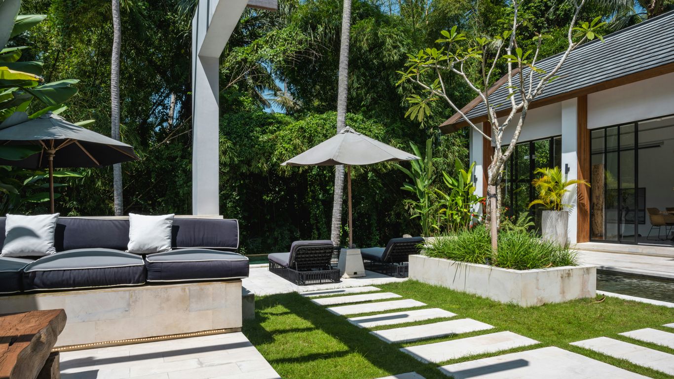 A patio with a couch, table and umbrellas