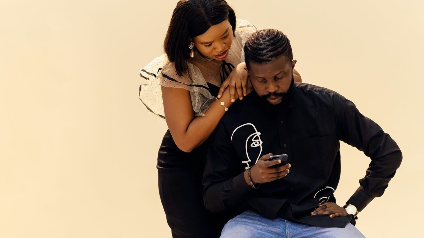 A man sitting on a woman's lap with a cell phone