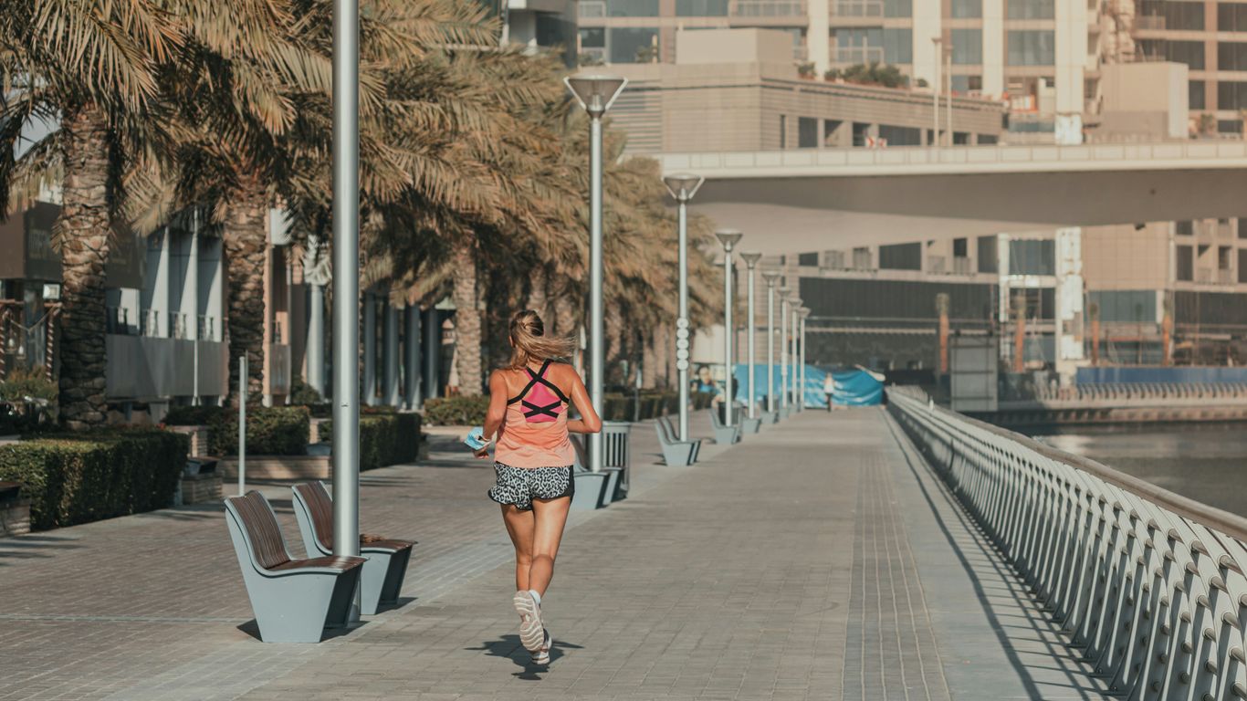 A woman walking down a sidewalk next to a body of water