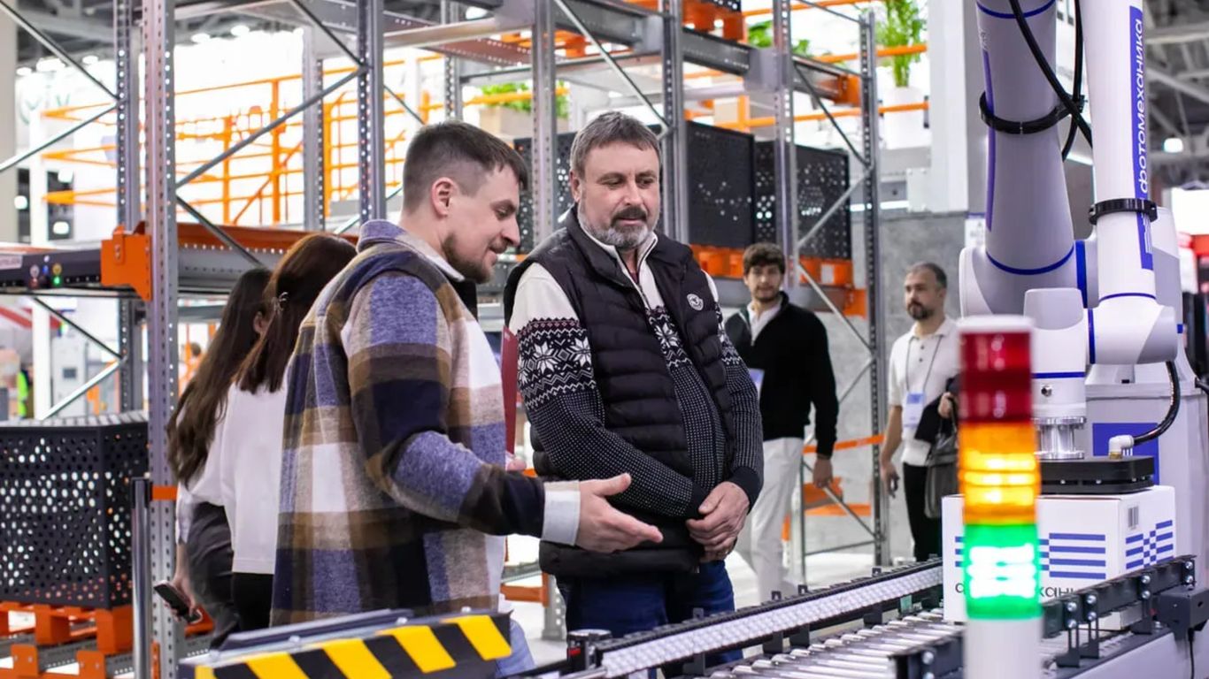 Men observe automated conveyor belt system in warehouse