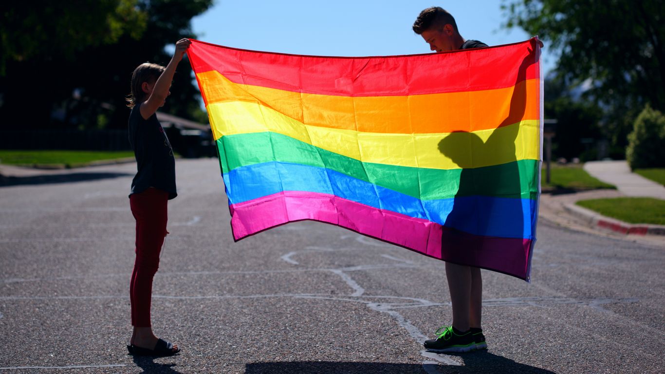 man and girl holding rainbow flag
