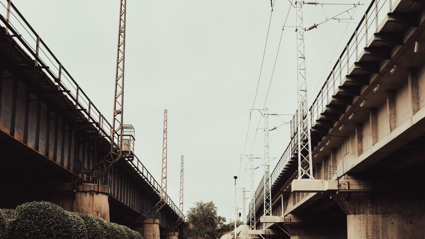 Two bridges with overhead power lines against sky