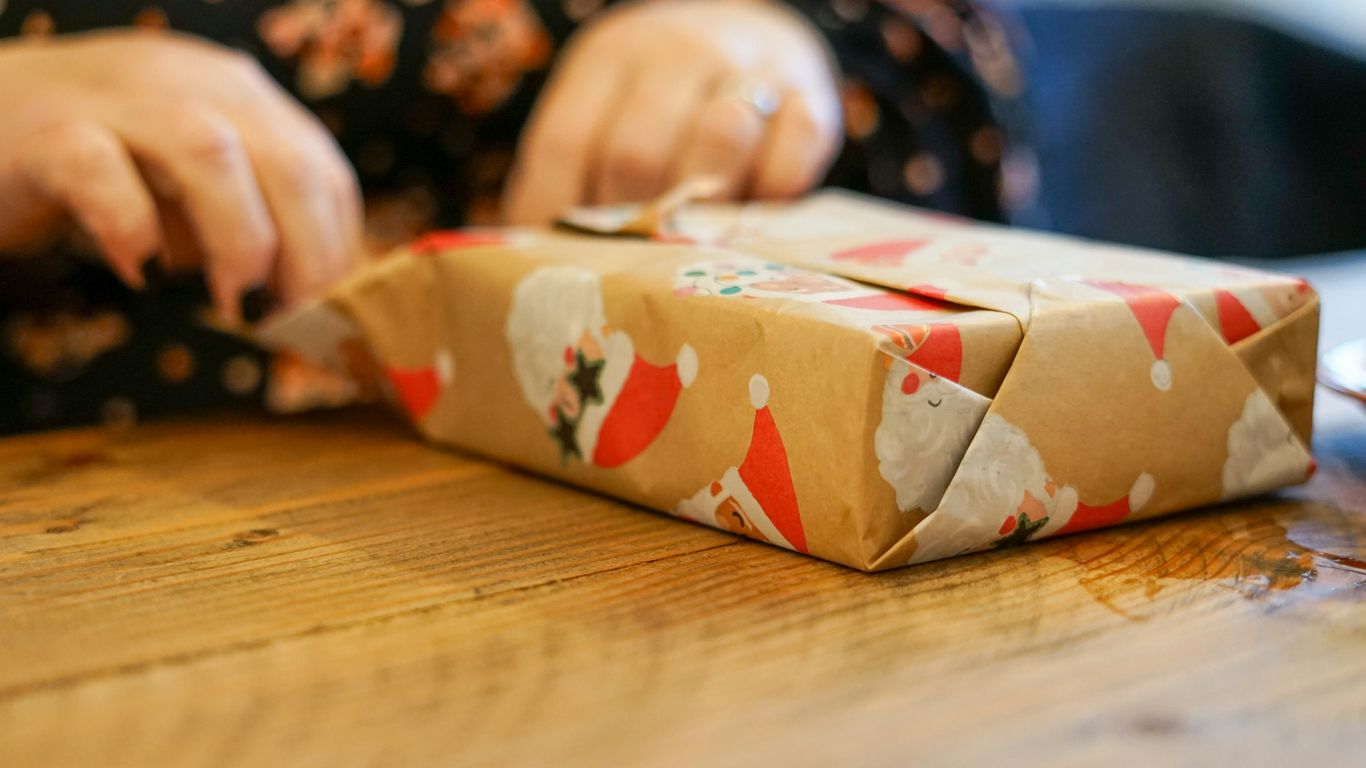 a person wrapping a present on a wooden table