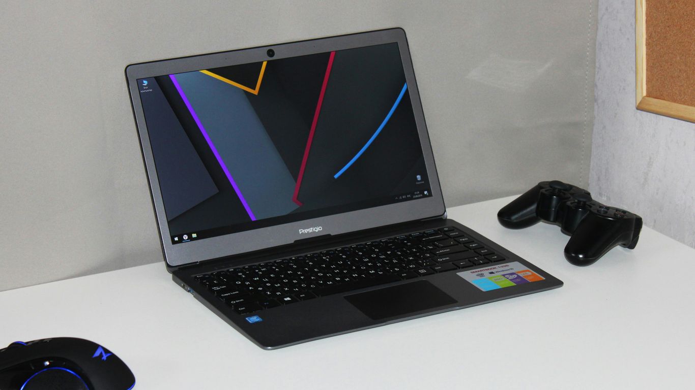 black and gray laptop computer near black wireless game controller on wooden table