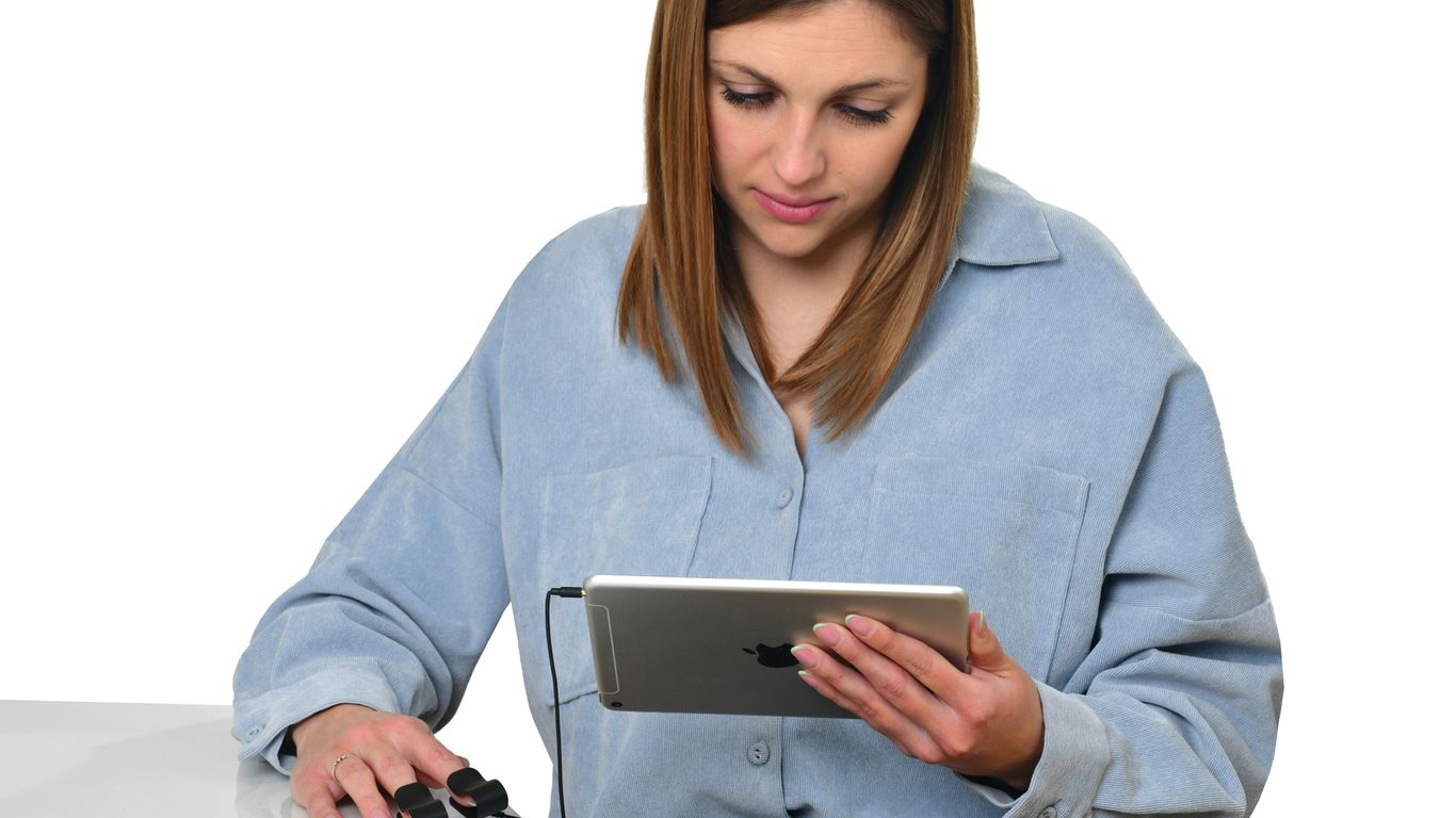 A woman sitting at a table looking at a tablet