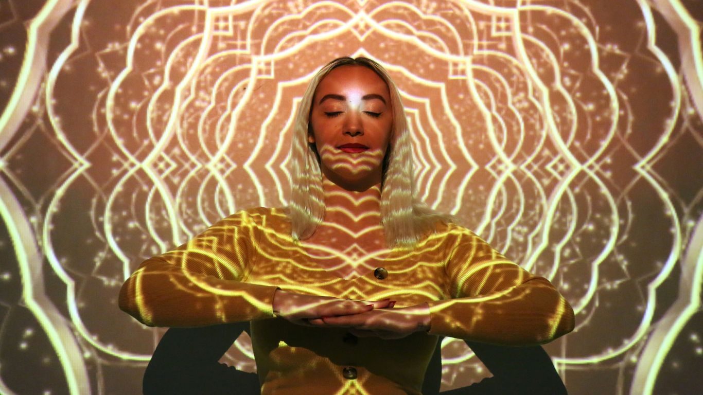 a woman in a yellow outfit is standing in front of a glowing background