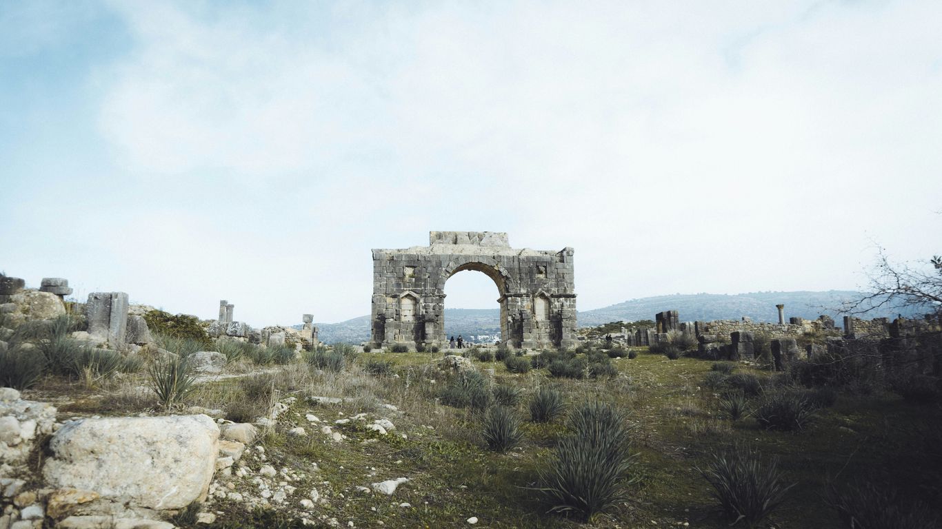 a stone arch in the middle of a field