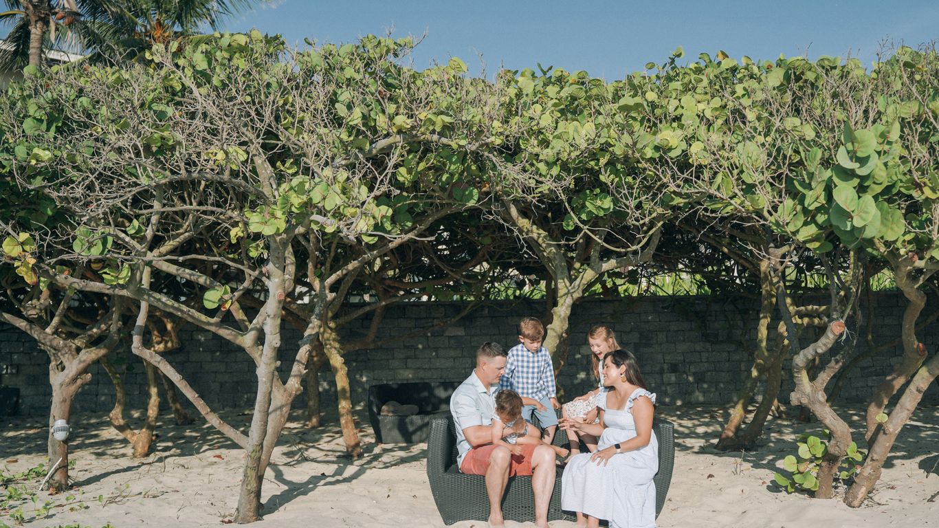 a group of people sitting on a bench under a tree