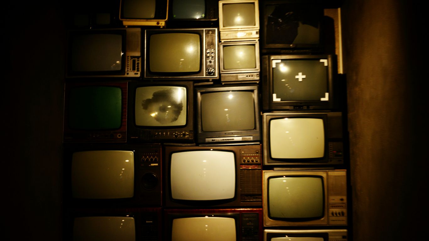 Stack of vintage televisions in dark room