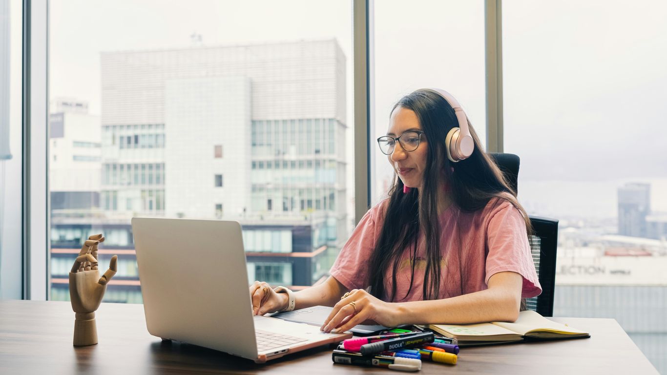 Young woman wearing headphones works on laptop