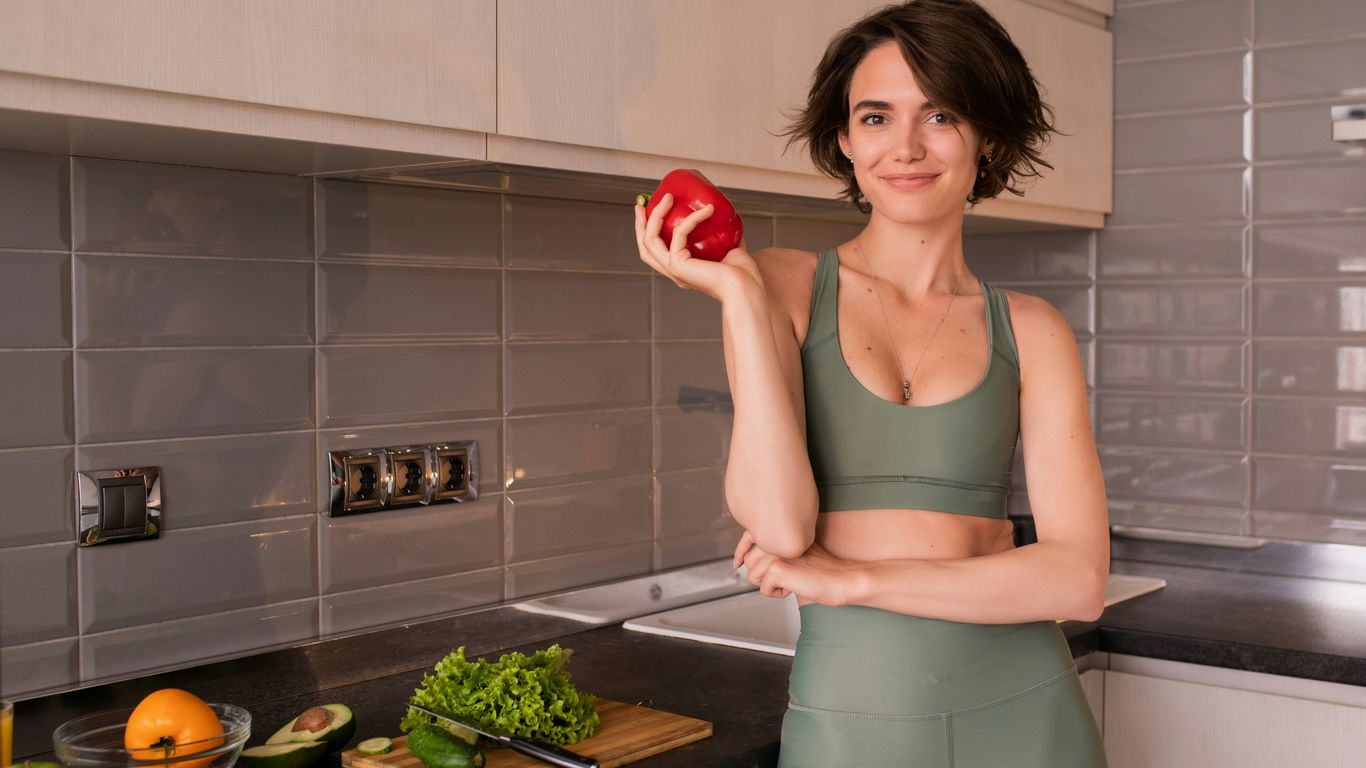a woman standing in a kitchen holding an apple