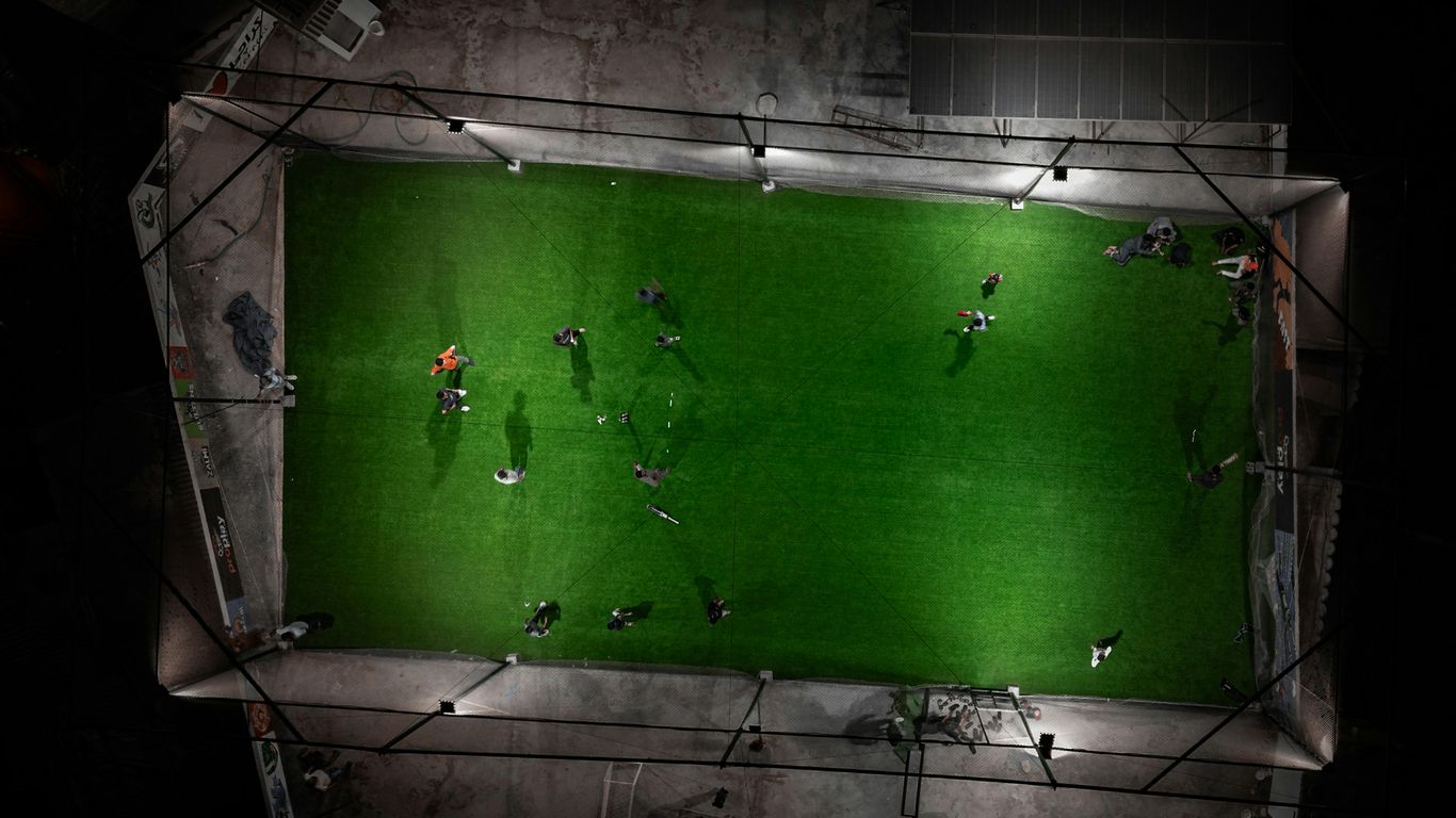 People playing soccer on a brightly lit field at night.