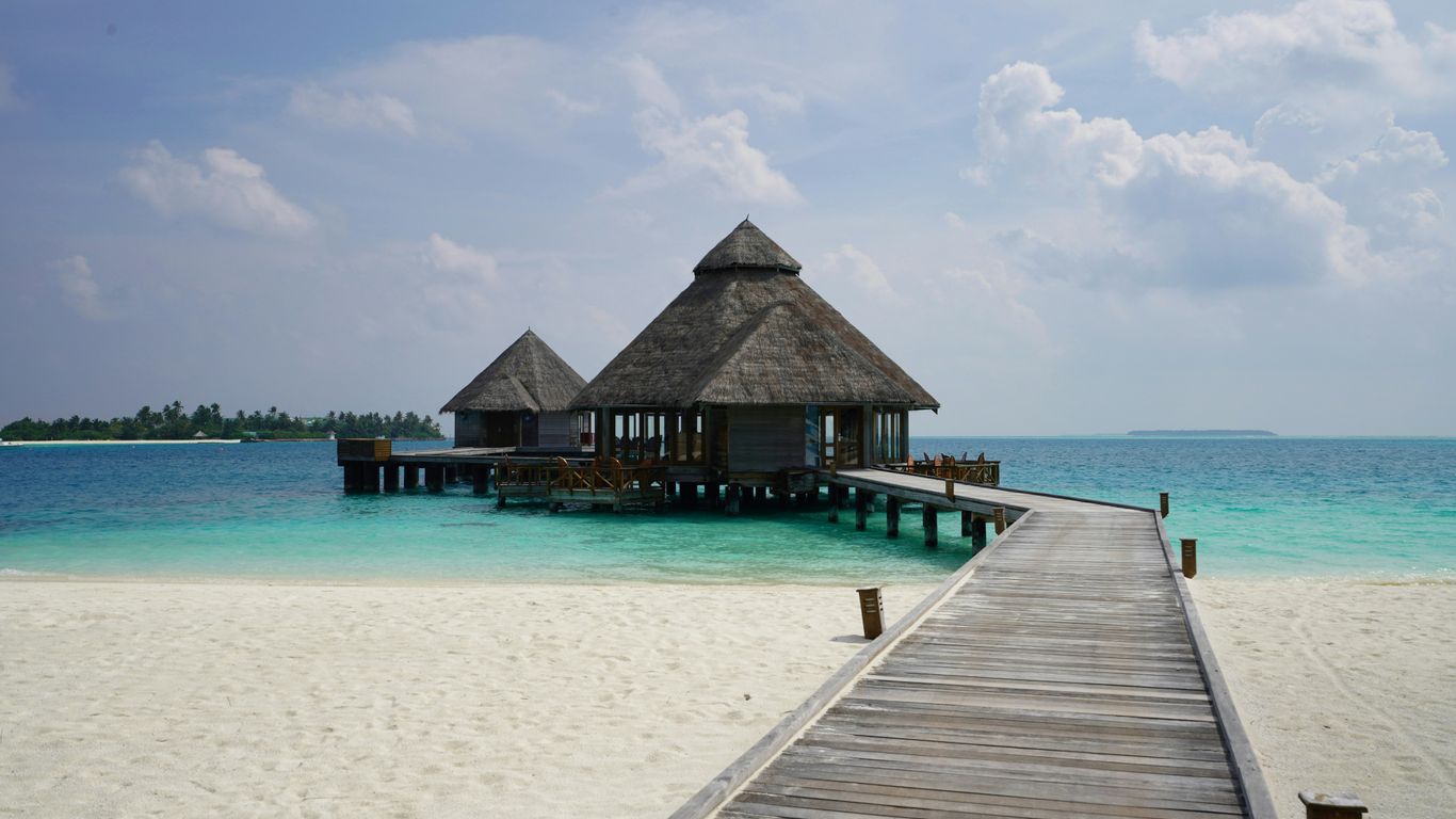 a pier leading to a beach with a hut on it