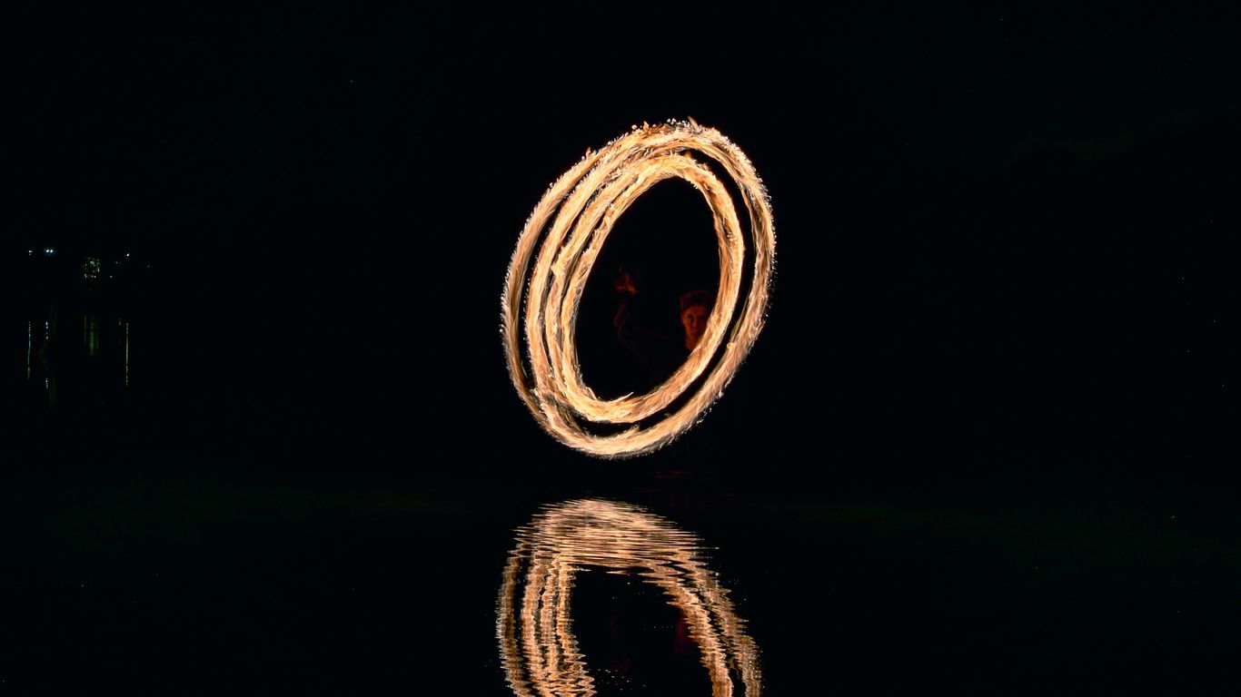 Fire dancer creates a glowing circle over water