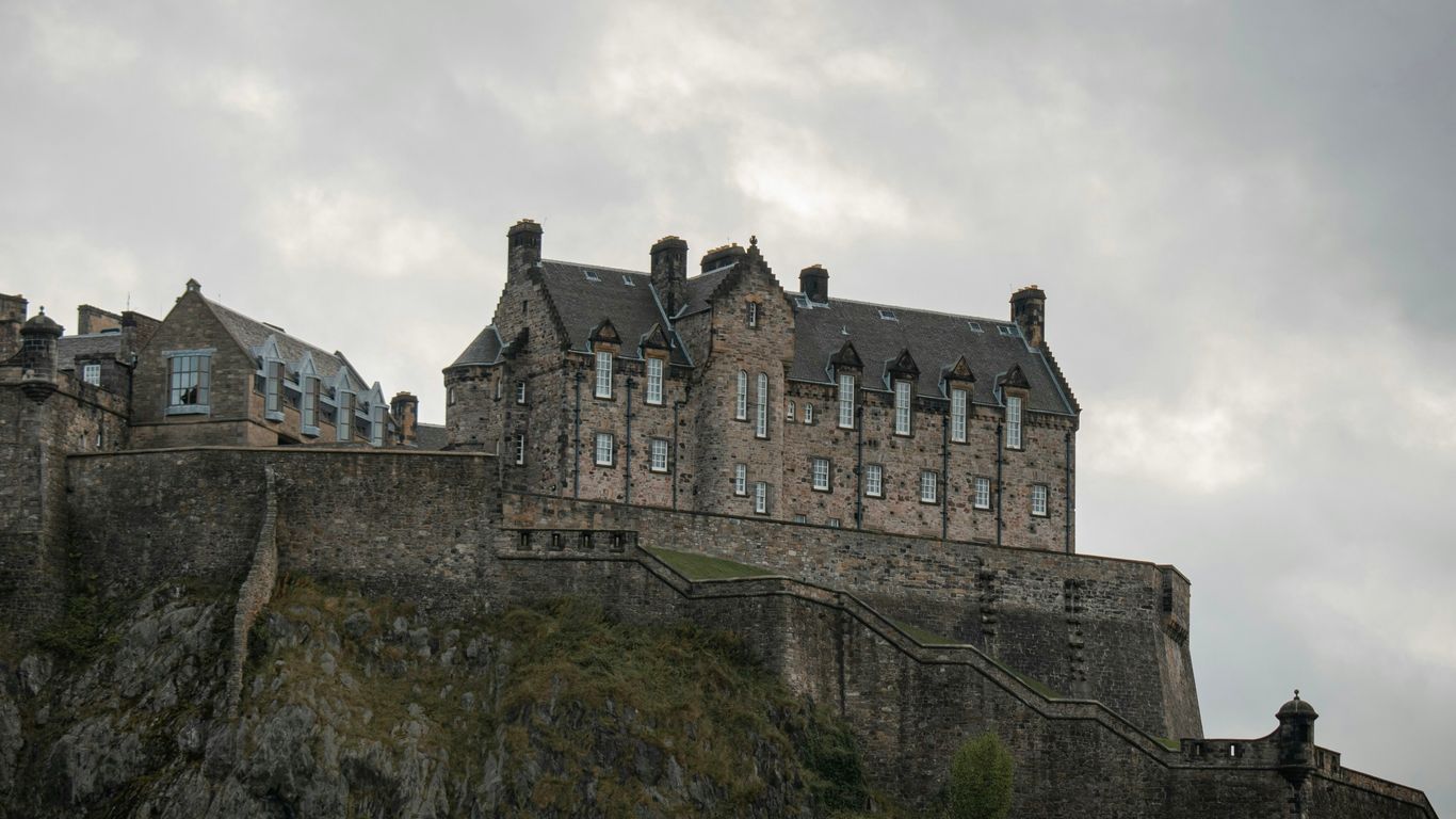 a castle on top of a hill with a cloudy sky