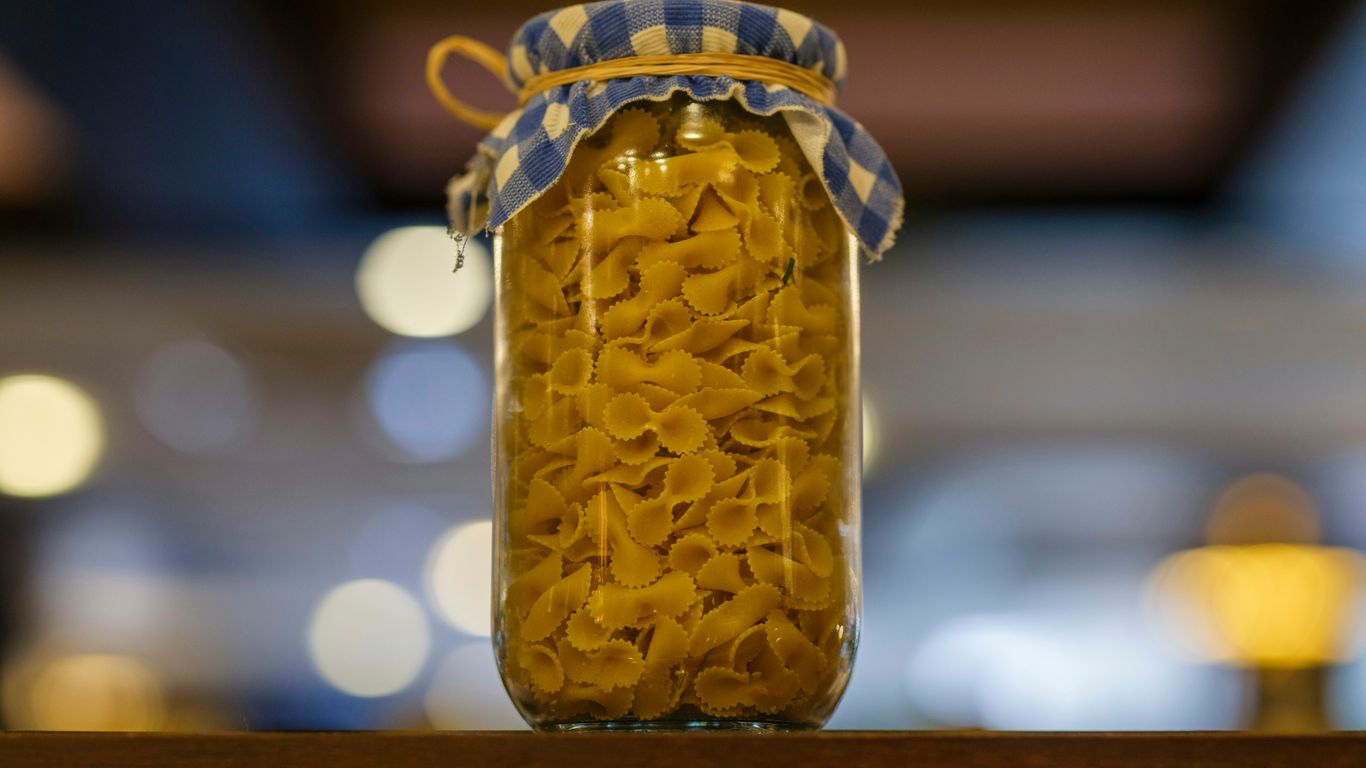 Pasta shells sit in a jar with a cloth lid.