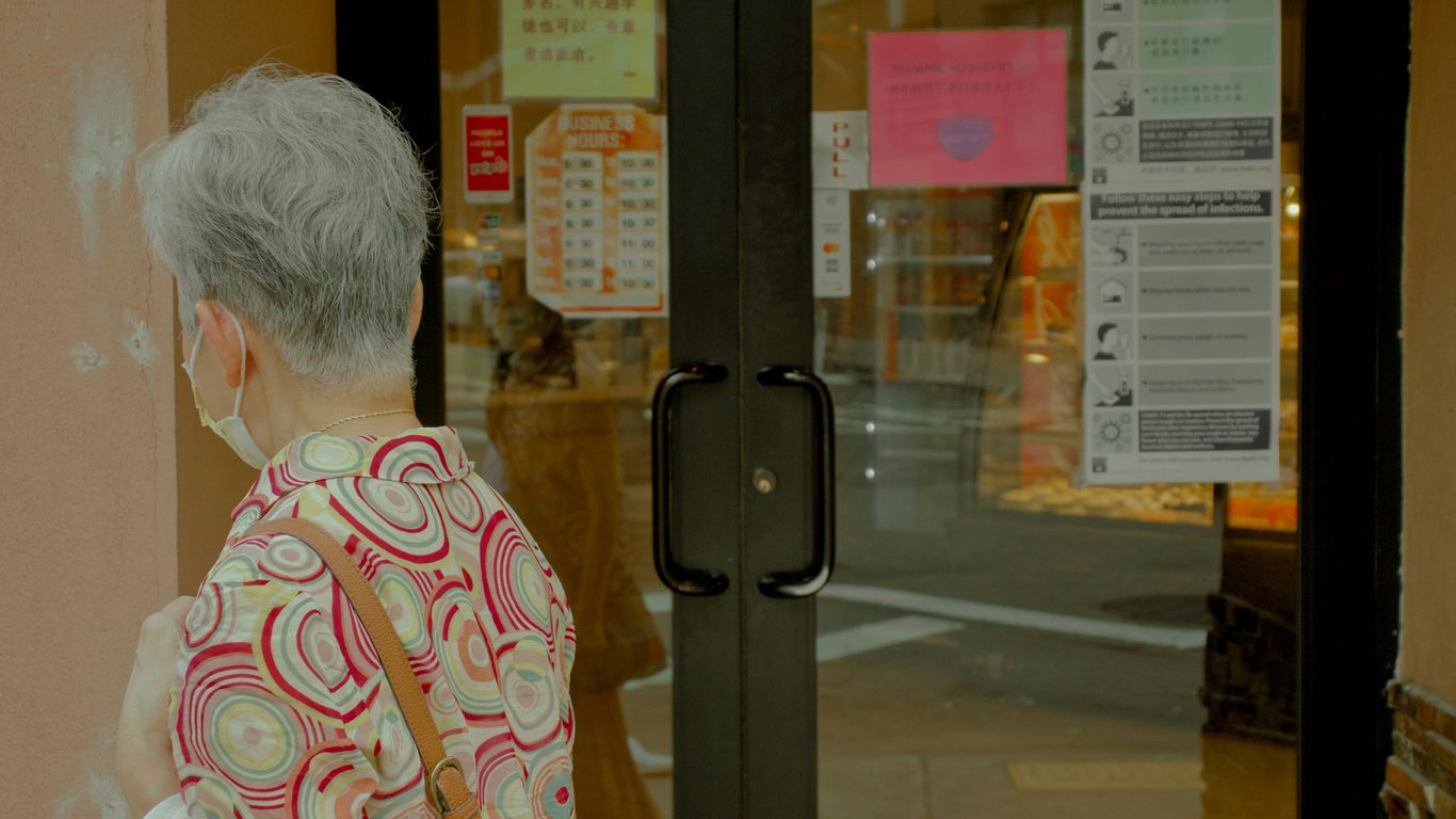 man in orange and white floral shirt standing near glass door